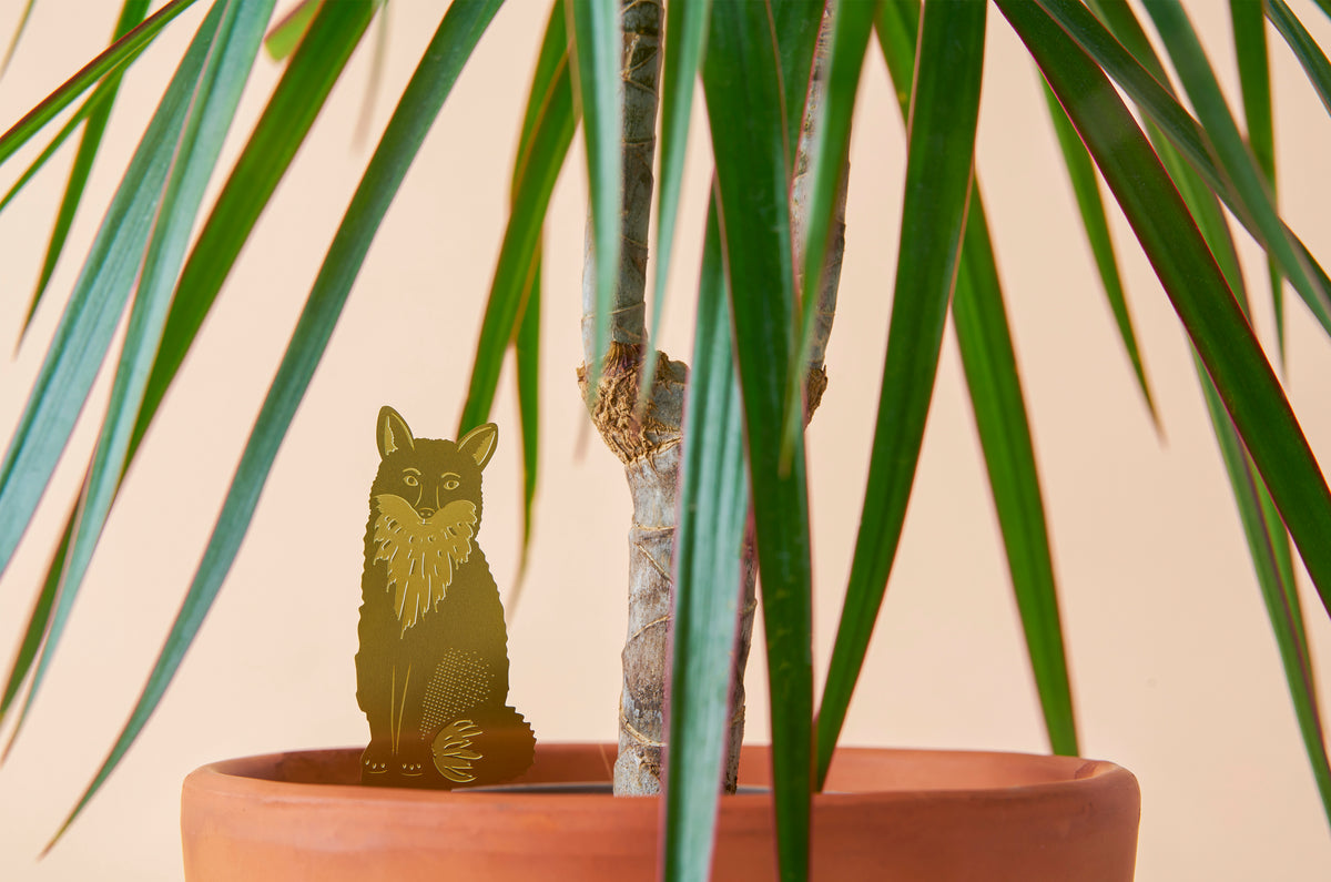 Messinge figur af en ræv siddende i en potteplante