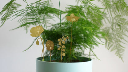 Forskellige små figurer af planter i messing stående i en potteplante